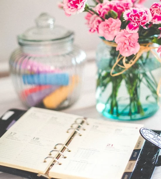 Notebook on table with flowers in vase